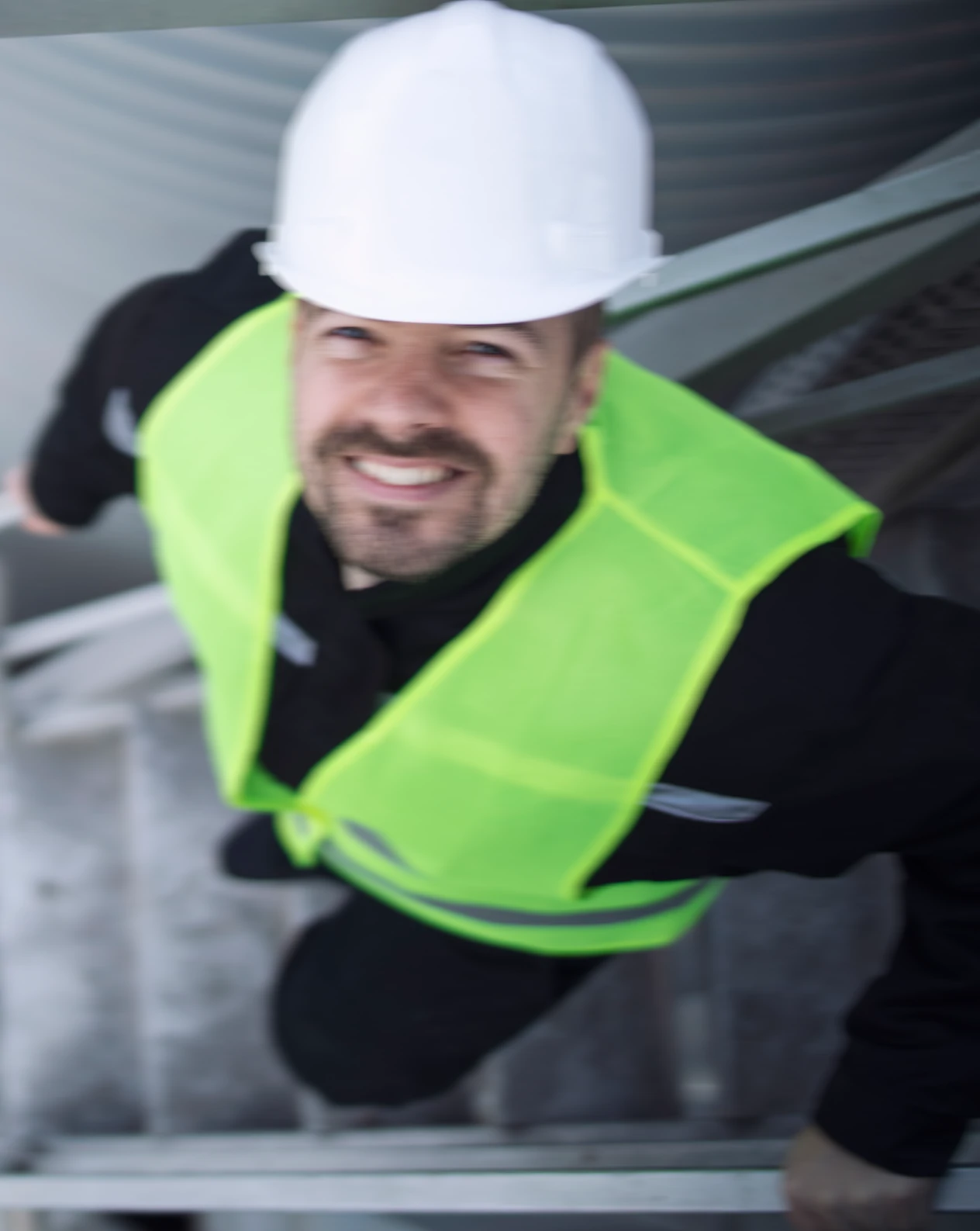Fachkraft für Arbeitssicherheit auf außenliegender Stahltreppe (zweiter Fluchtweg) bei einer Betriebsbegehung mit Helm und Warnweste, design by Freepik